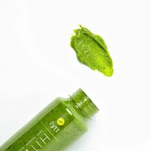 Green Detoxifying Exfoliating Mask spilled from an open bottle showing creamy textured skincare product on white background